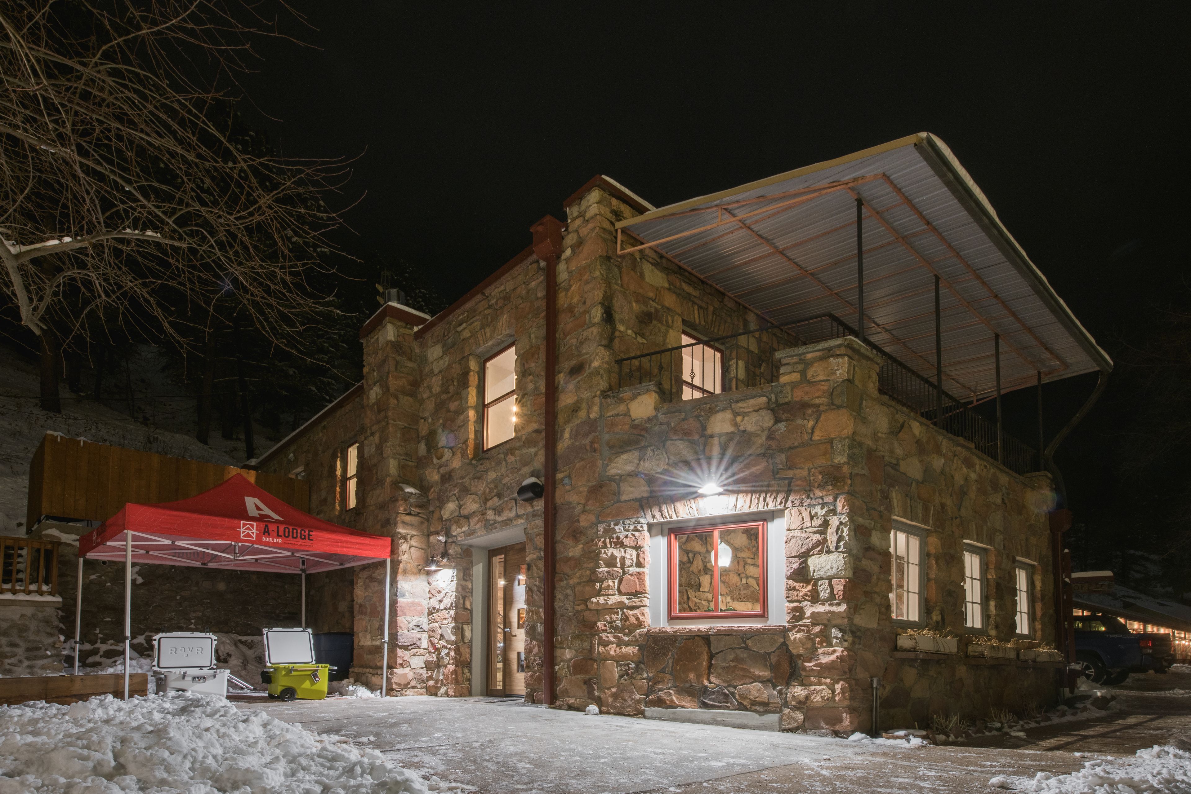 Un edificio de piedra con una carpa roja que dice "A LODGE" y un espacio al aire libre cubierto.