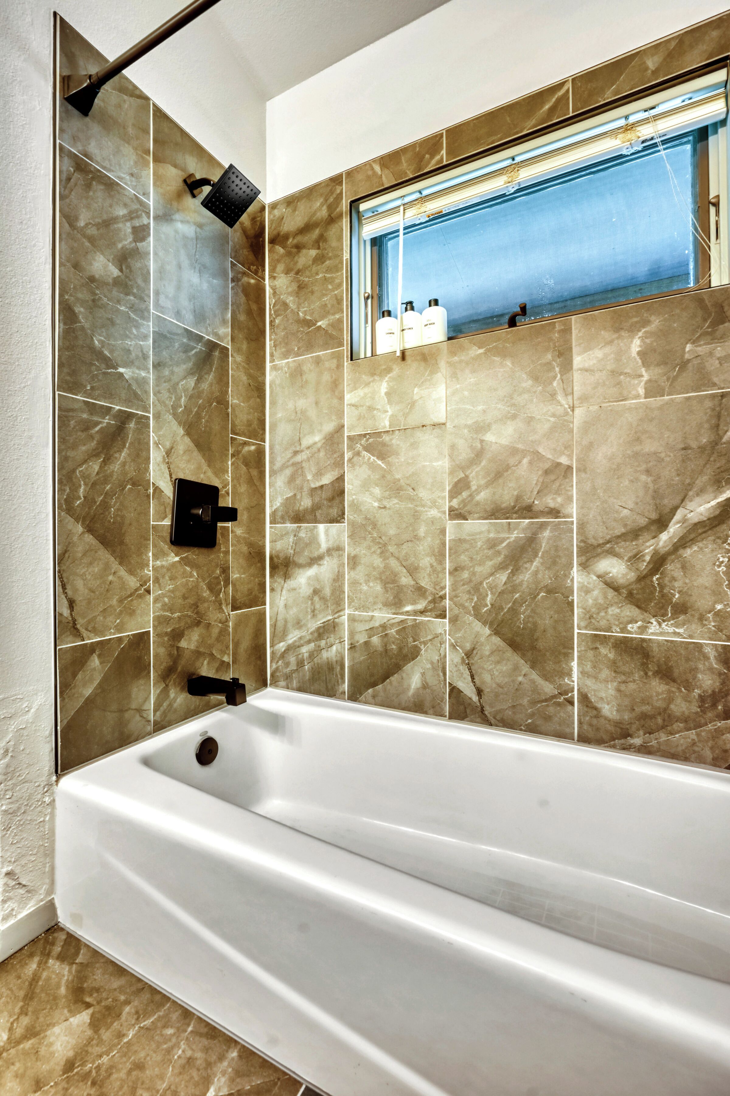Un baño moderno con una bañera grande, un cabezal de ducha y un espejo sobre la bañera.