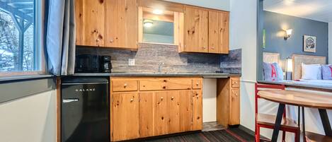 Una cocina compacta con armarios de madera, lavavajillas negro y una pequeña encimera.