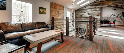 A modern living room with a leather sofa, a wooden coffee table, and a patterned carpet.