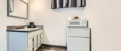 A compact kitchenette with a sink, a coffee maker, a microwave, and a refrigerator.