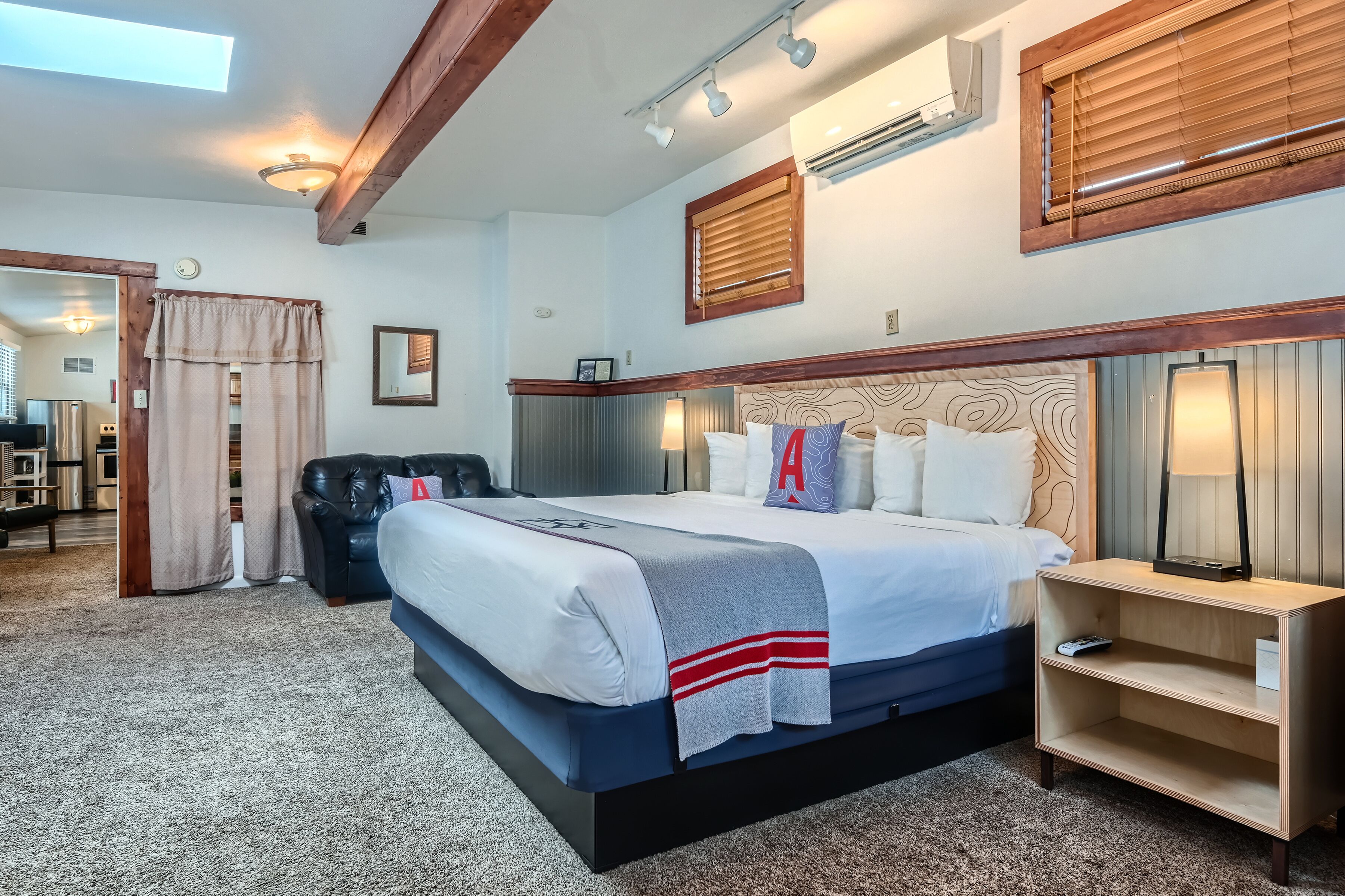A hotel room with a large bed, a wooden headboard, a bedside table, and a mirror.