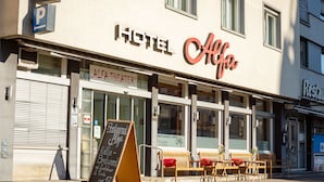 A hotel named "Alfa" with a signboard, a theater entrance, and outdoor seating. - Alfa Hotel (Birsfelden)
