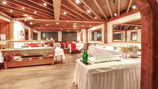 A spacious hall with wooden beams, tables set for dining, and a bar area. - Alfa Hotel (Birsfelden)