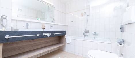 A modern bathroom with a wooden vanity, a white toilet, and a glass shower enclosure.