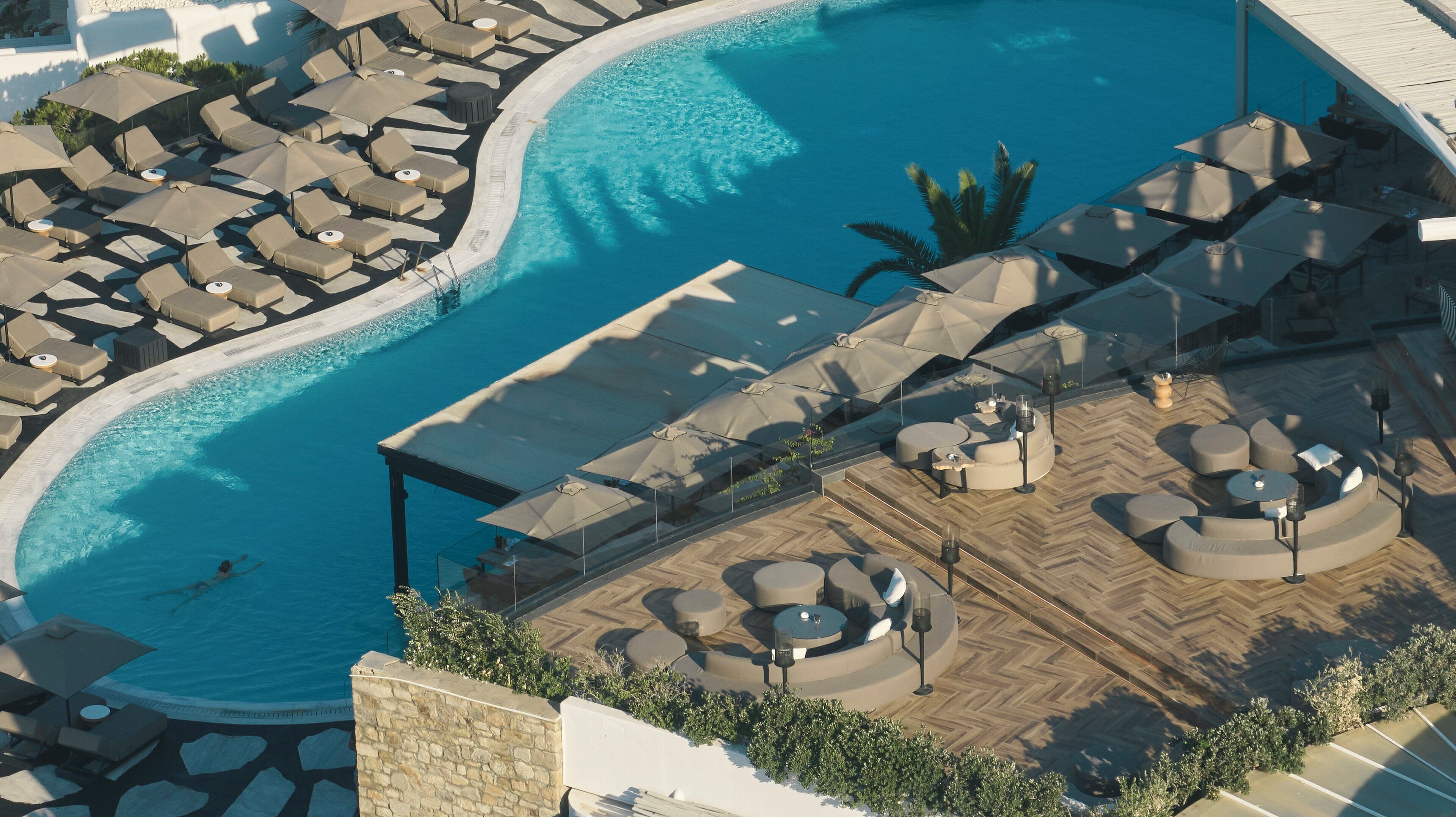 An aerial view of a resort with a large pool, sun loungers, and outdoor seating areas.