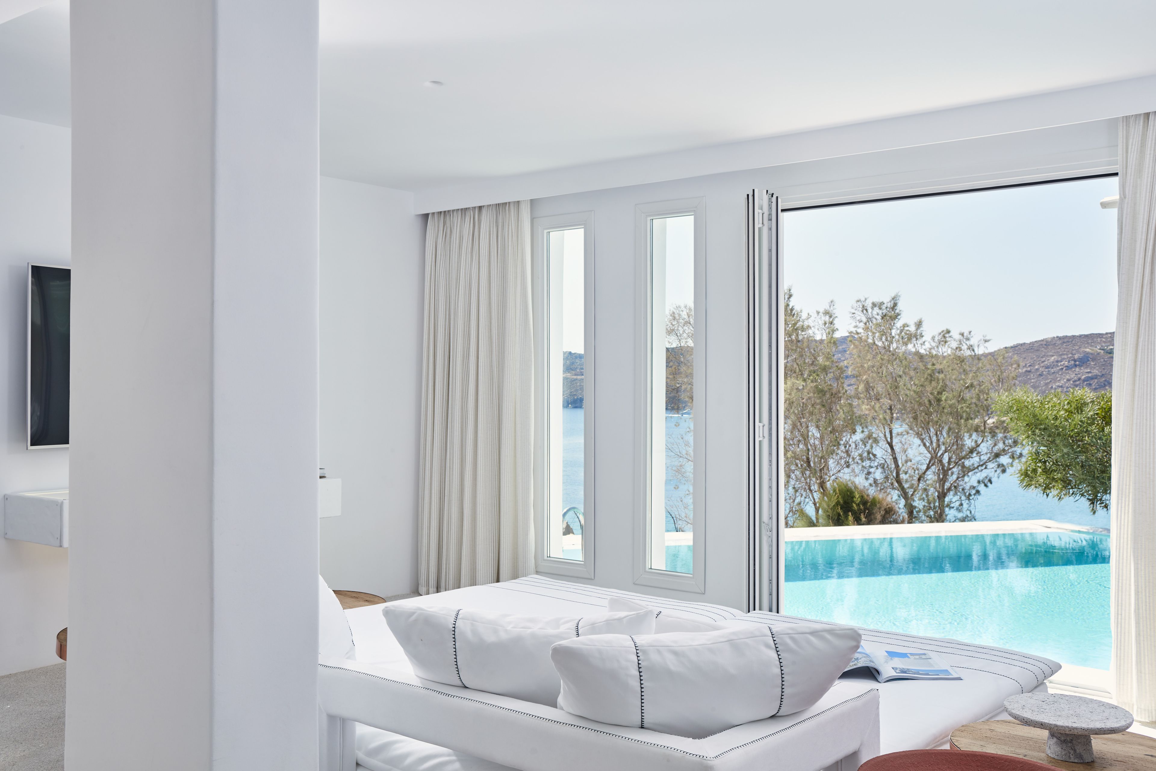 A modern bedroom with a large window overlooking a pool and a scenic view.