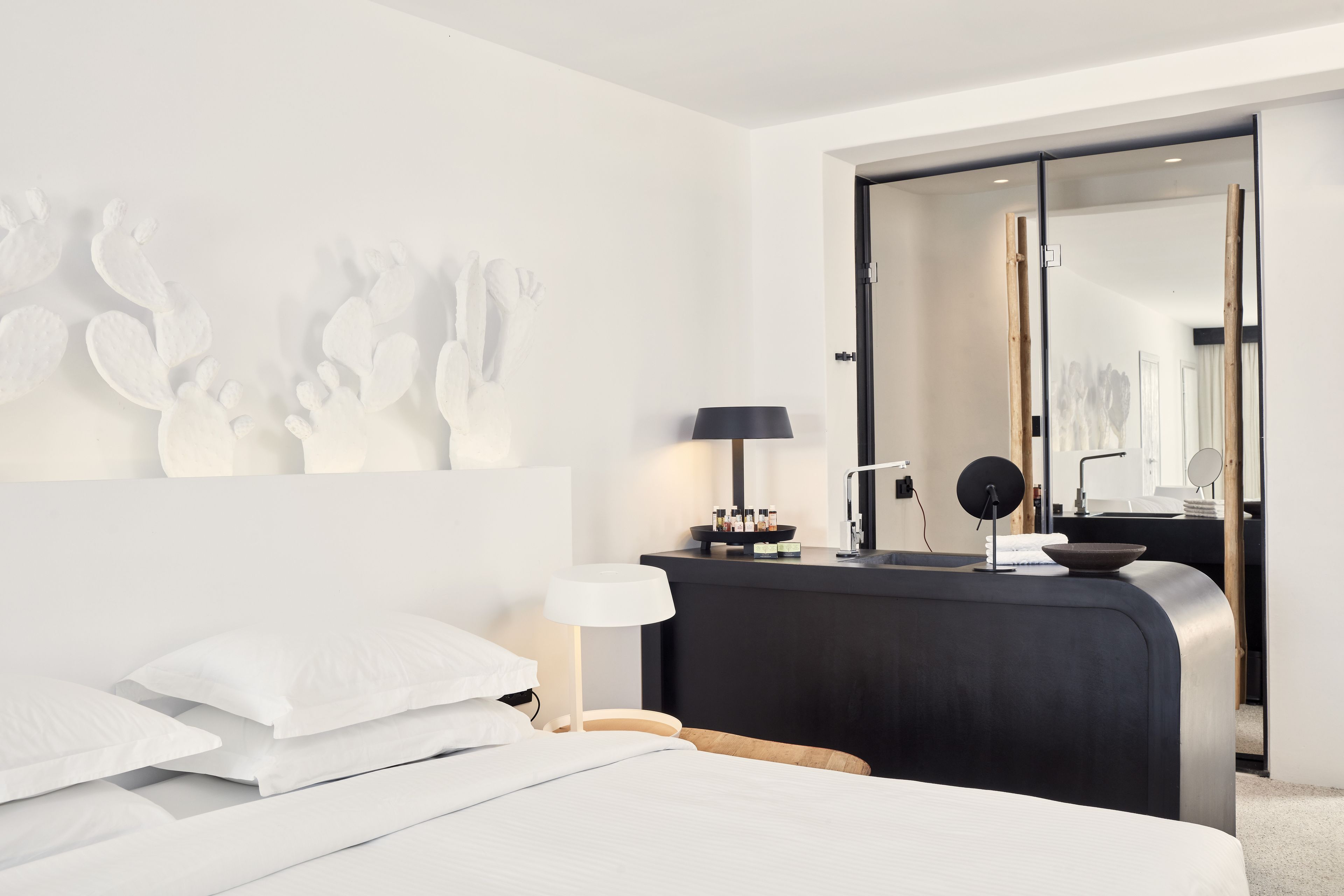 Una habitación de hotel moderna con cama, mesita de noche, lámpara y espejo.