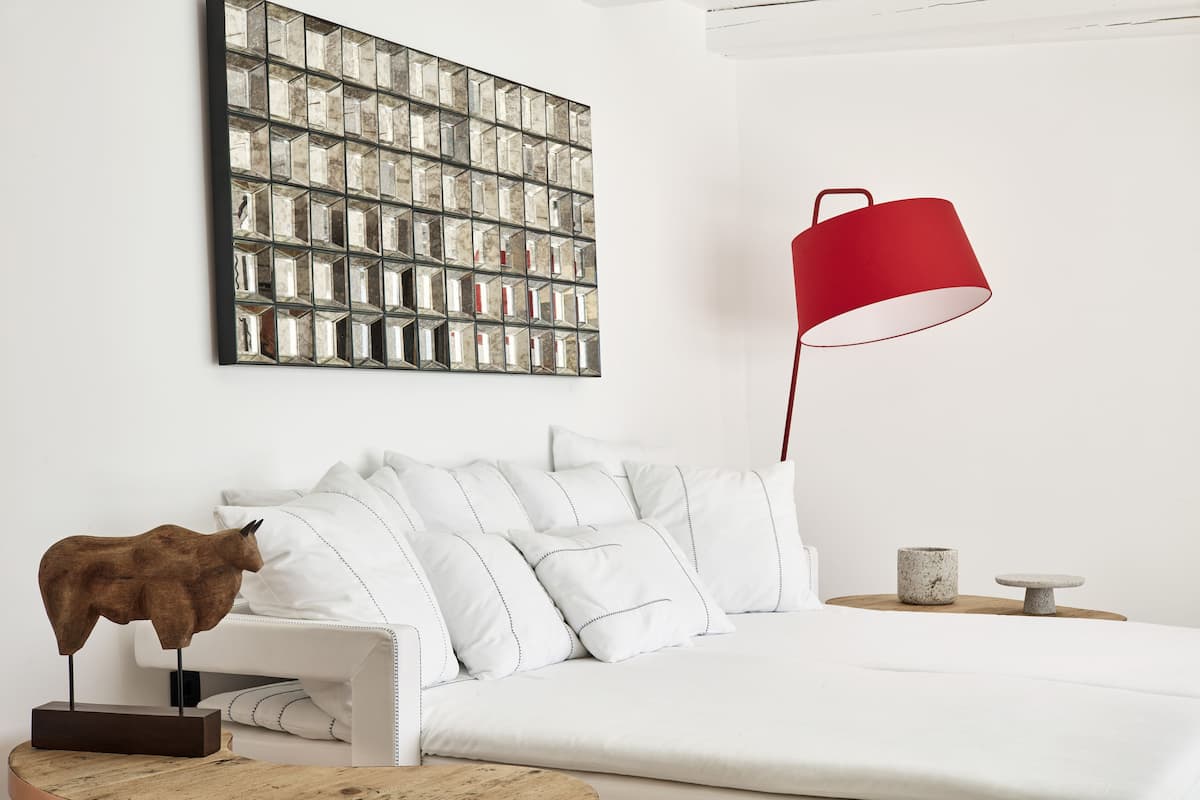 Ett modernt vardagsrum med en vit soffa, en röd golvlampa, en dekorativ djurskulptur och ett konstverk på väggen.