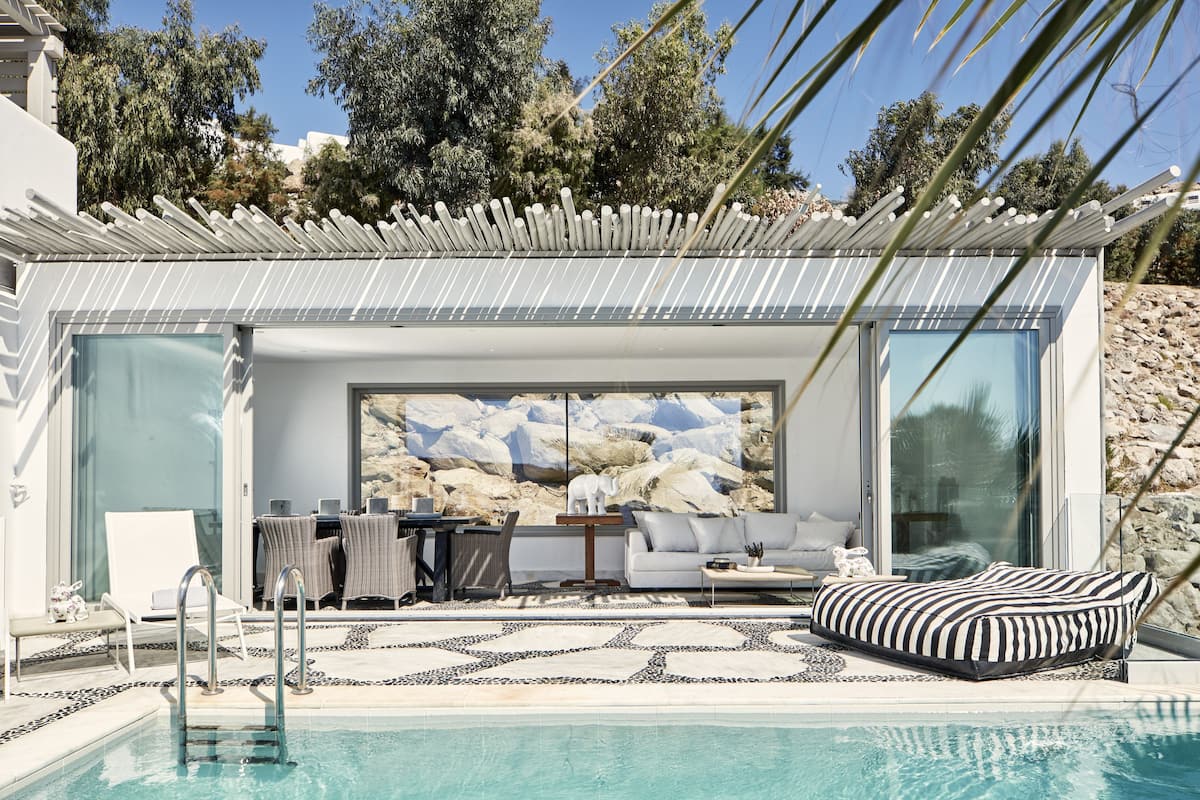 A modern outdoor pool area with a sofa, lounge chairs, and a dining table.