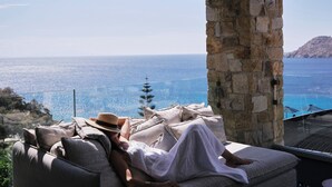 Una persona relajándose en un sofá con vista al mar y una pared de piedra.