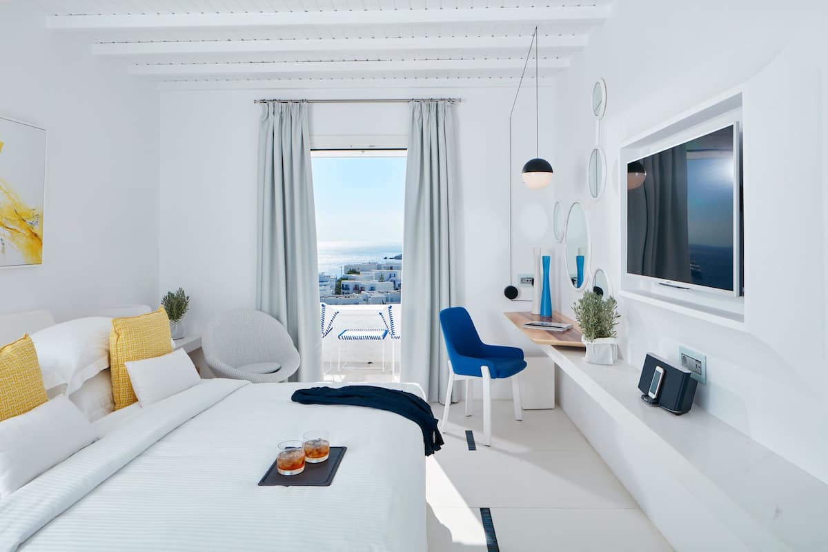 Een moderne hotelkamer met een groot bed, een bureau, een stoel, een televisie en een balkon met uitzicht.