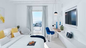 Ein modernes Hotelzimmer mit einem großen Bett, einem Schreibtisch, einem Sessel, einem Fernseher und einem Balkon mit Blick.