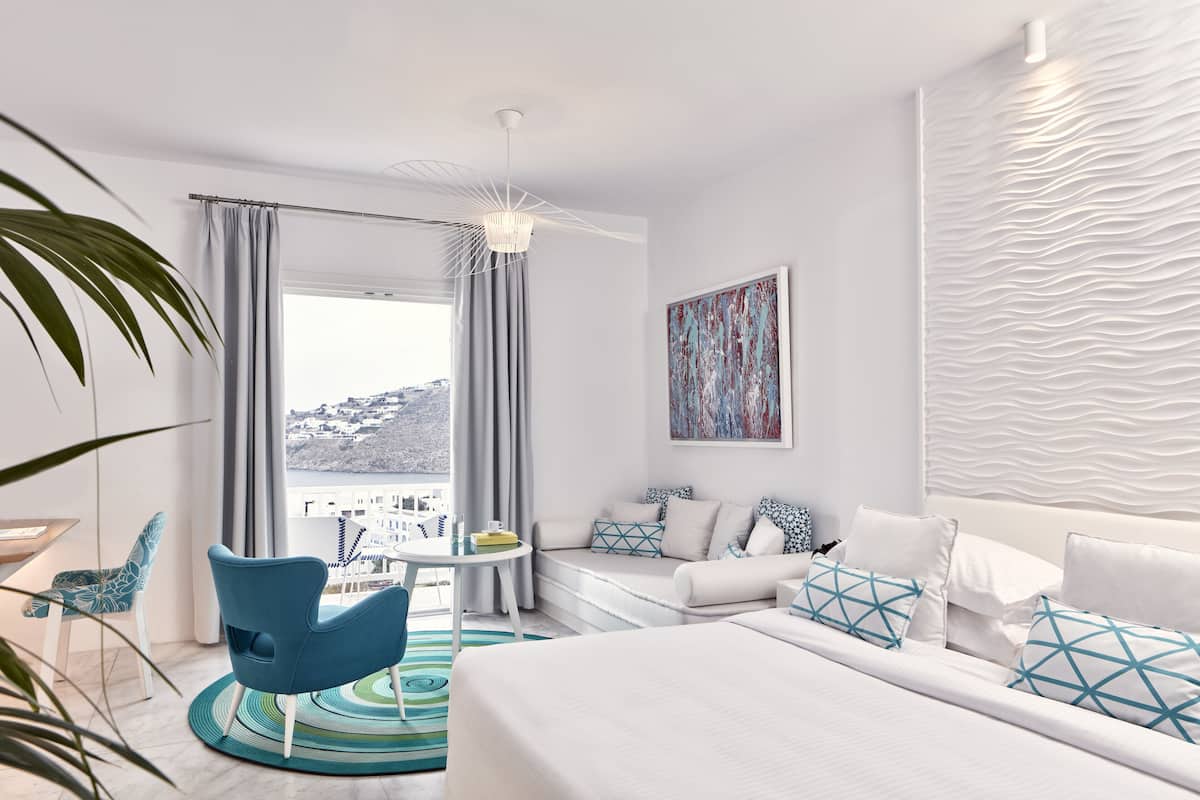 Een moderne hotelkamer met een groot bed, een bank, een eettafel en uitzicht op de stad.