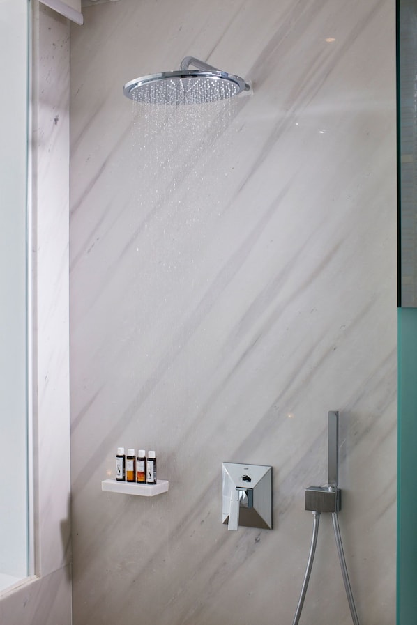 A shower with a rain head, a soap dispenser, and a control panel.