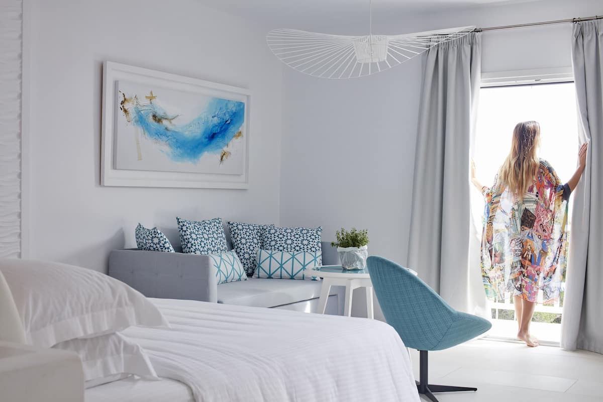 Een moderne slaapkamer met een bed, een bank, een stoel en een raam met gordijnen.