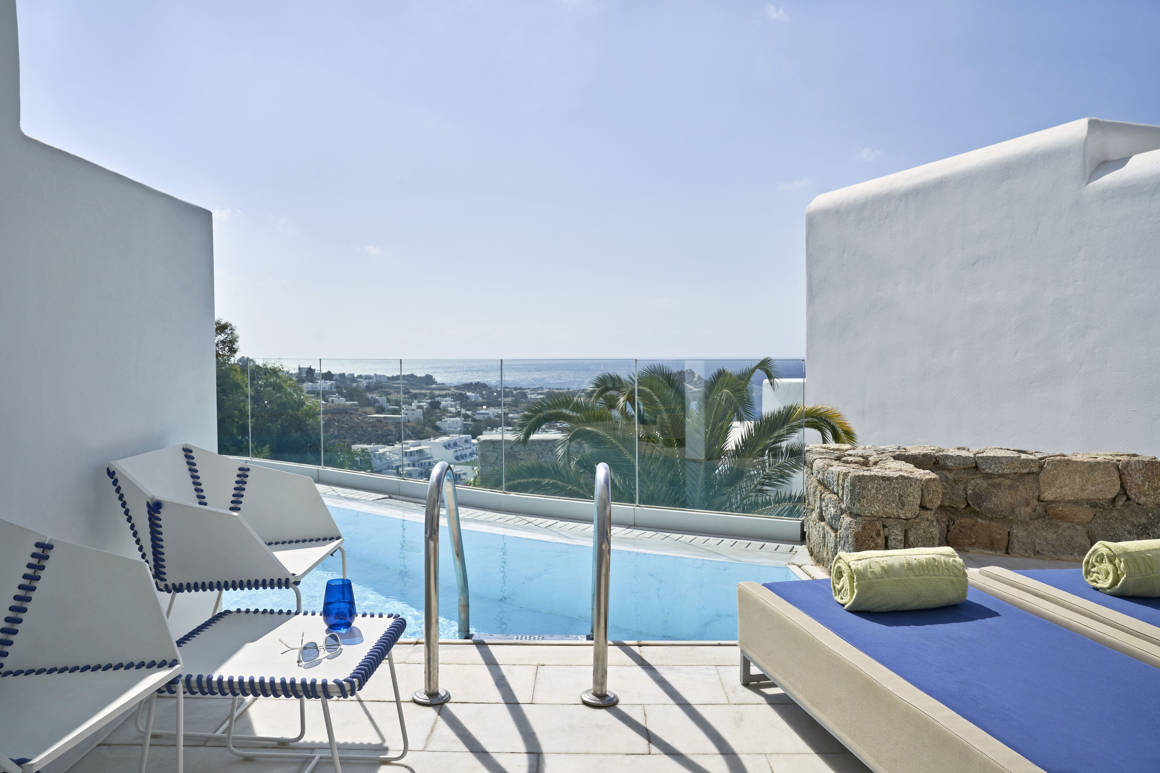 Zona de piscina con sillones de descanso y vista a la ciudad.