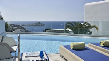 Ein Poolbereich mit Blick auf das Meer, eine Liege, ein Notizblock und ein blaues Glas.
