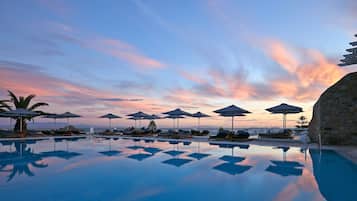 Relax by the serene pool surrounded by sun loungers and umbrellas.