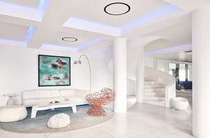 Un interior moderno con un sofá blanco, un sillón rojo único y un cuadro en la pared.