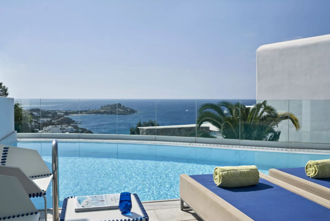 A poolside area with lounge chairs, a sun lounger, and a view of the ocean.