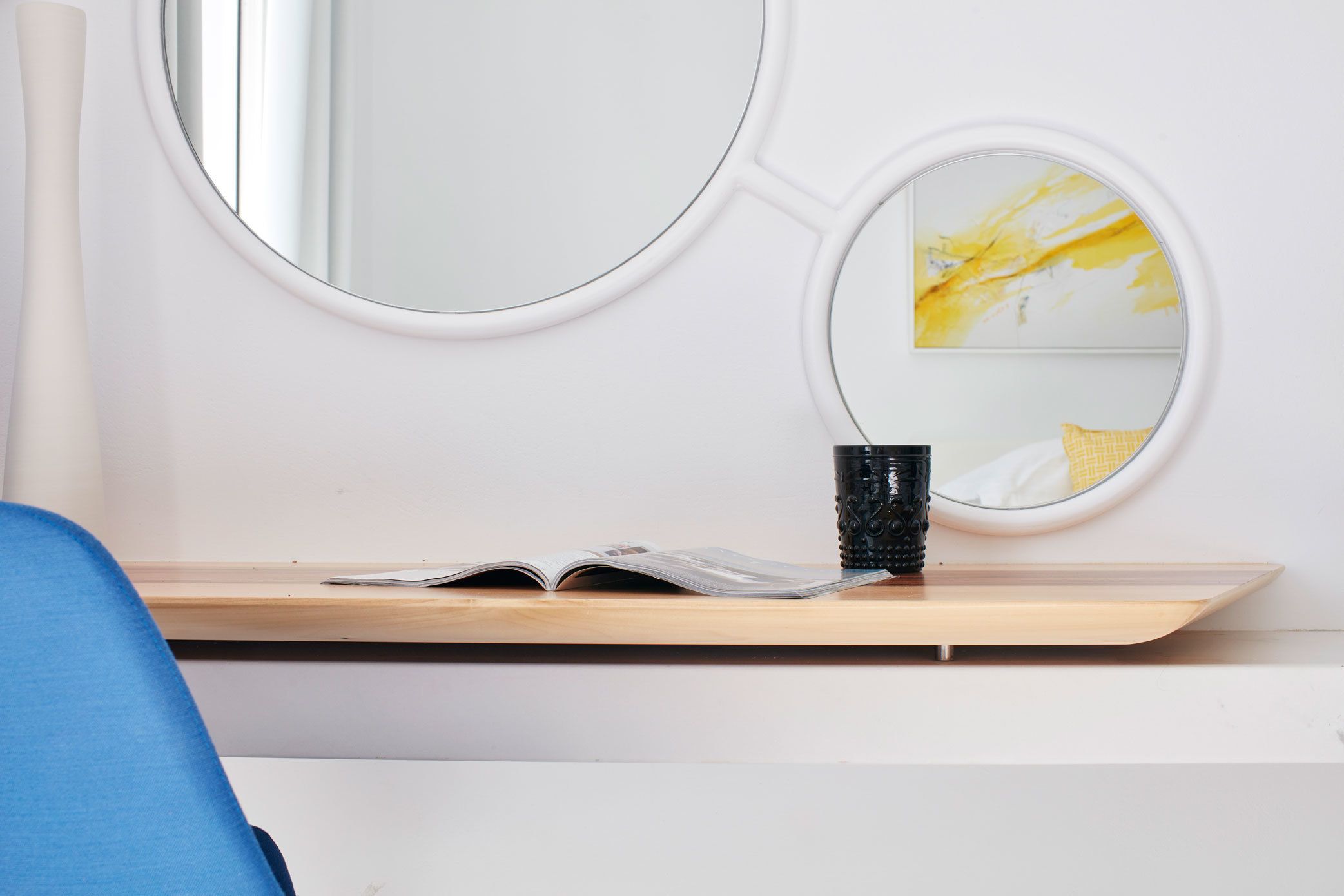 Una habitación con un escritorio de madera, un espejo y un pequeño cuadro.