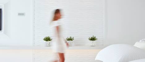 Un dormitorio moderno con una cama, una mesita de noche con dos plantas en macetas y una pared con textura.