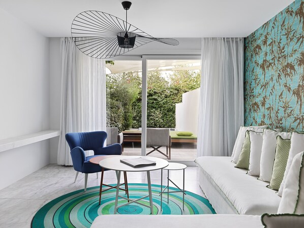 Een moderne woonkamer met een bank, een blauwe fauteuil, een bijzettafeltje en een unieke lamp.