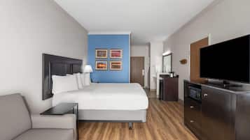 A hotel room with a bed, a desk, a television, and a bathroom visible in the background.