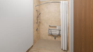A shower area with a grab bar, a showerhead, and a towel rack.