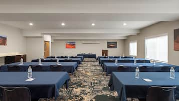 A conference room with rows of tables, chairs, and water bottles.
