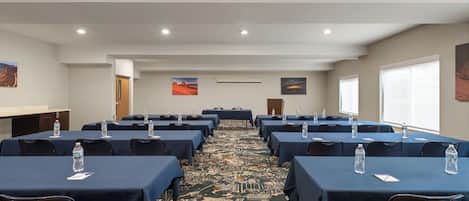 A conference room with rows of tables, chairs, and water bottles.