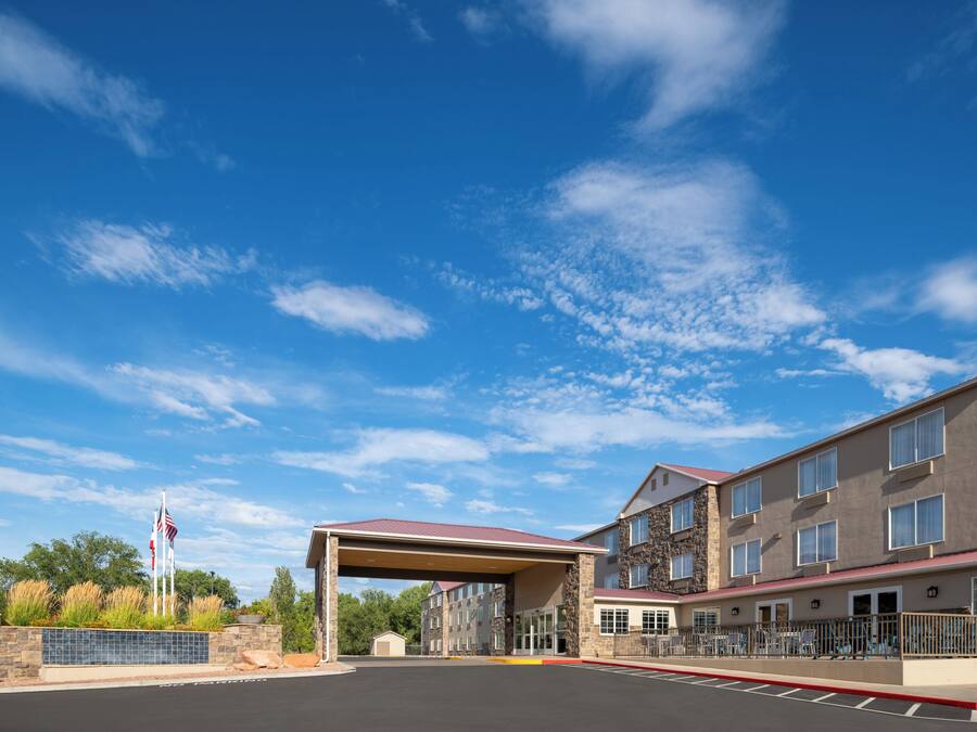 A hotel entrance with a covered driveway, stone facade, and flagpole.