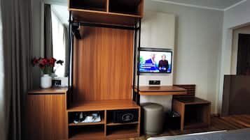 Una habitación de hotel moderna con una unidad de entretenimiento de madera, un televisor, una mesita y una cama.