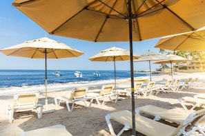Na praia, espreguiçadeiras, guarda-sóis, toalhas de praia 
