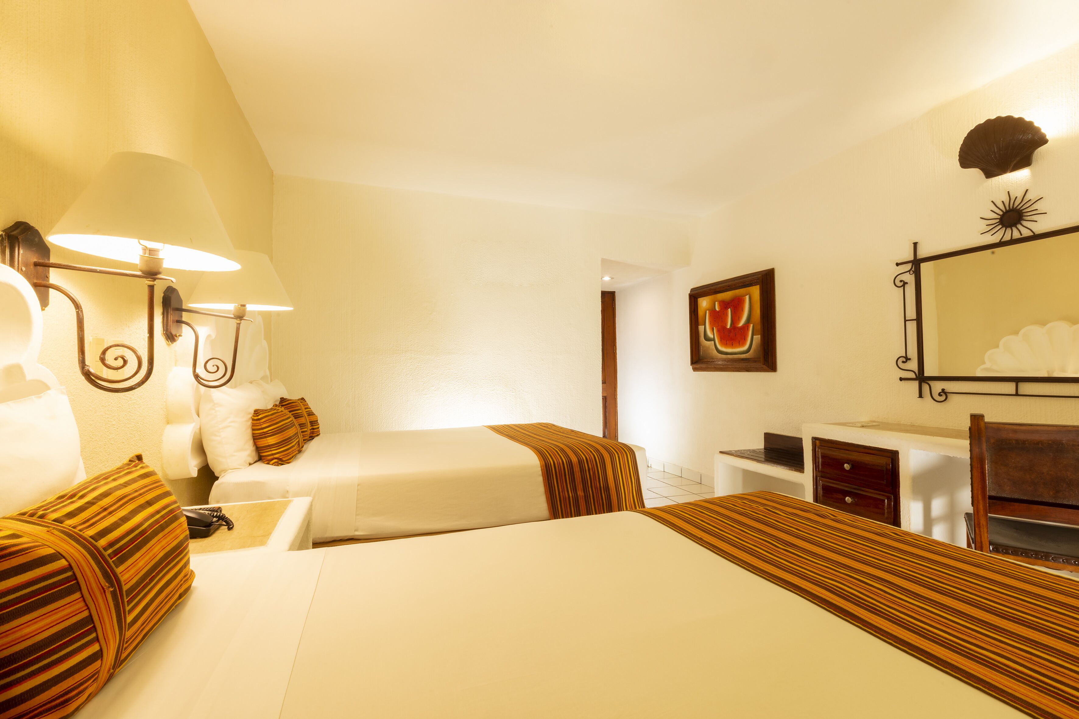 Een hotelkamer met twee bedden, een bureau, een stoel, een lamp en een spiegel aan de muur.