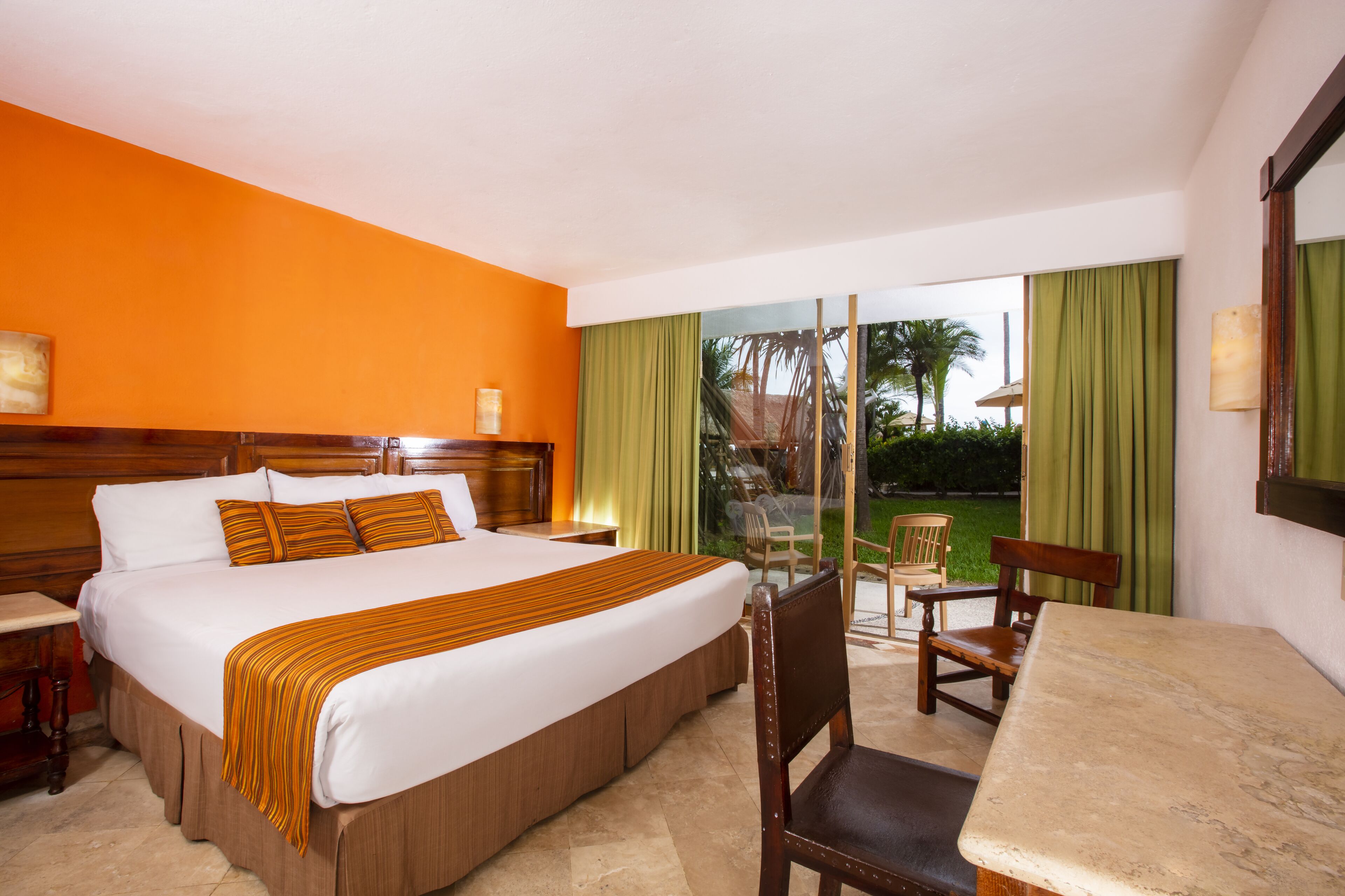A hotel room with a large bed, a wooden headboard, a desk, and a chair.