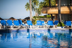 A poolside area with blue lounge chairs and a clear view of the ocean. - Las Palmas by the Sea All Inclusive (Puerto Vallarta)
