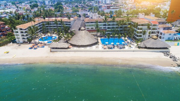 An aerial view of a resort with multiple buildings, a beach, and a swimming pool. - Las Palmas by the Sea All Inclusive (Puerto Vallarta)
