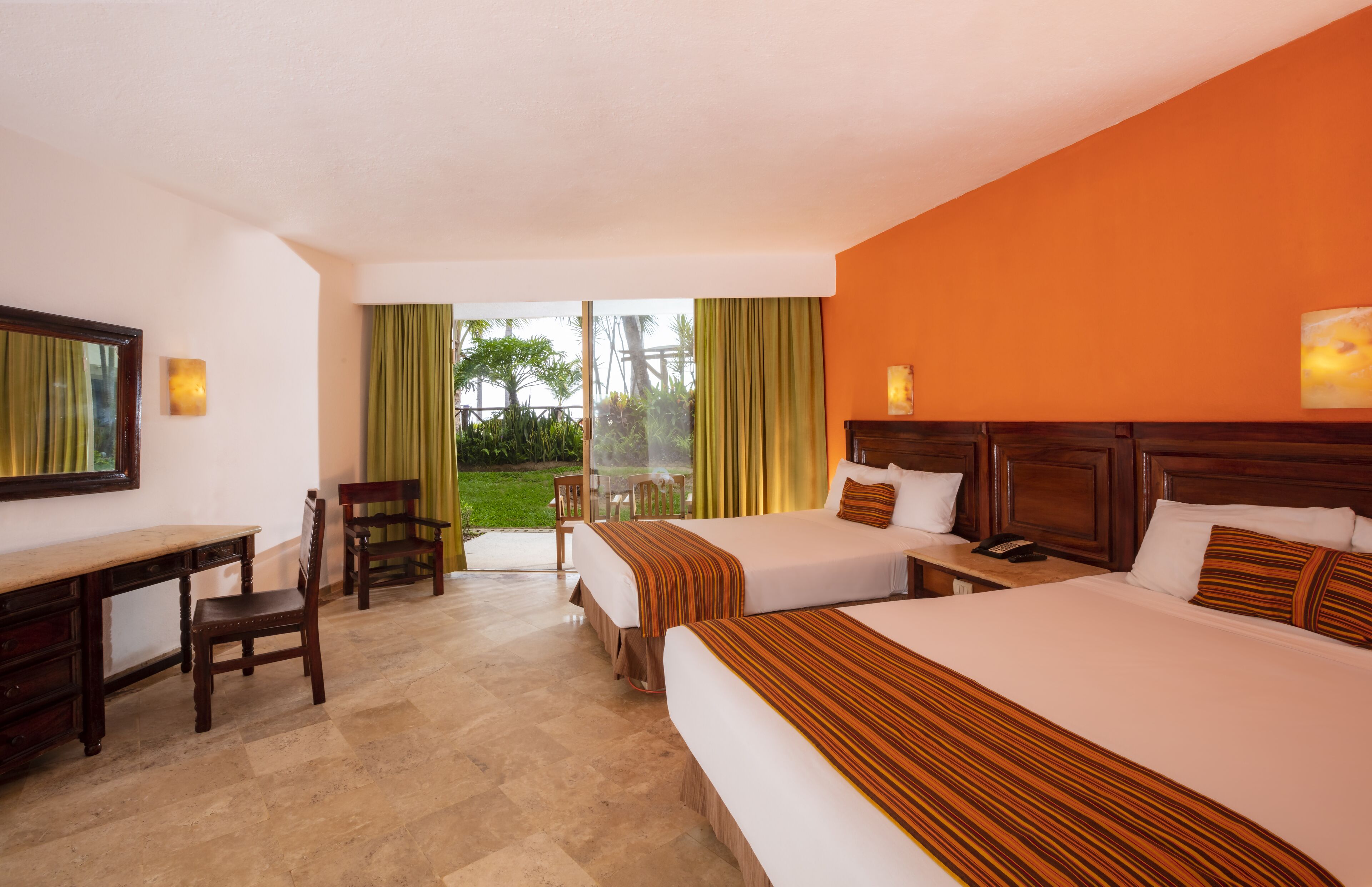 A hotel room with two beds, a desk, and a chair.