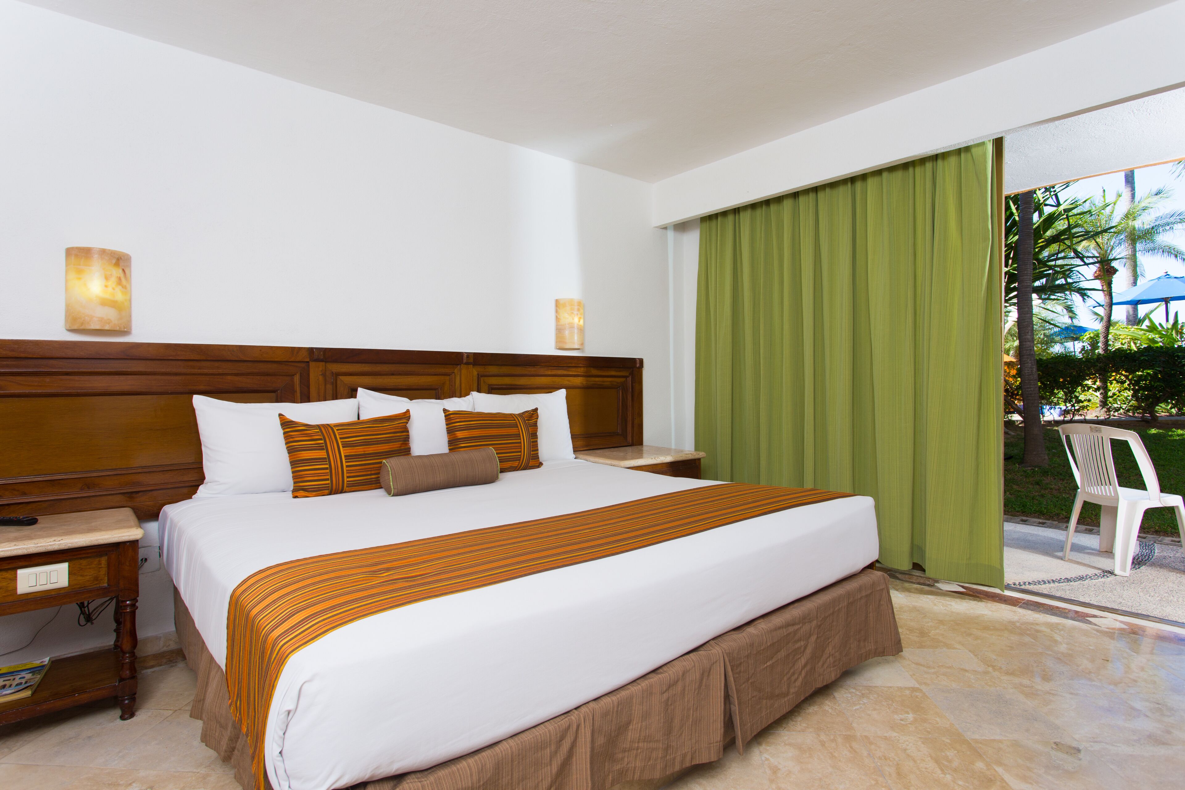 Une chambre d’hôtel avec un grand lit, une tête de lit en bois et une vue sur l’extérieur grâce à une porte coulissante.