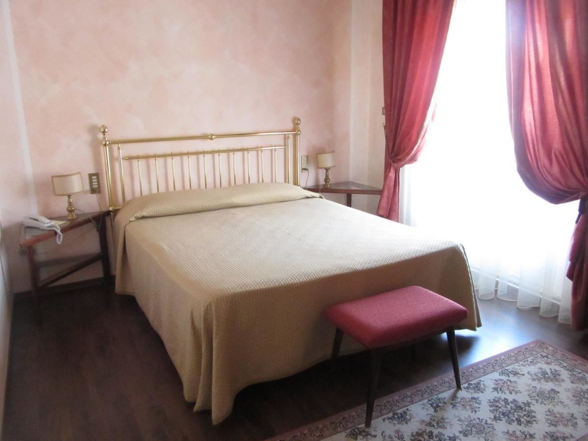 A bedroom with a bed, bedside tables, a nightstand, a bench, and a window with curtains.