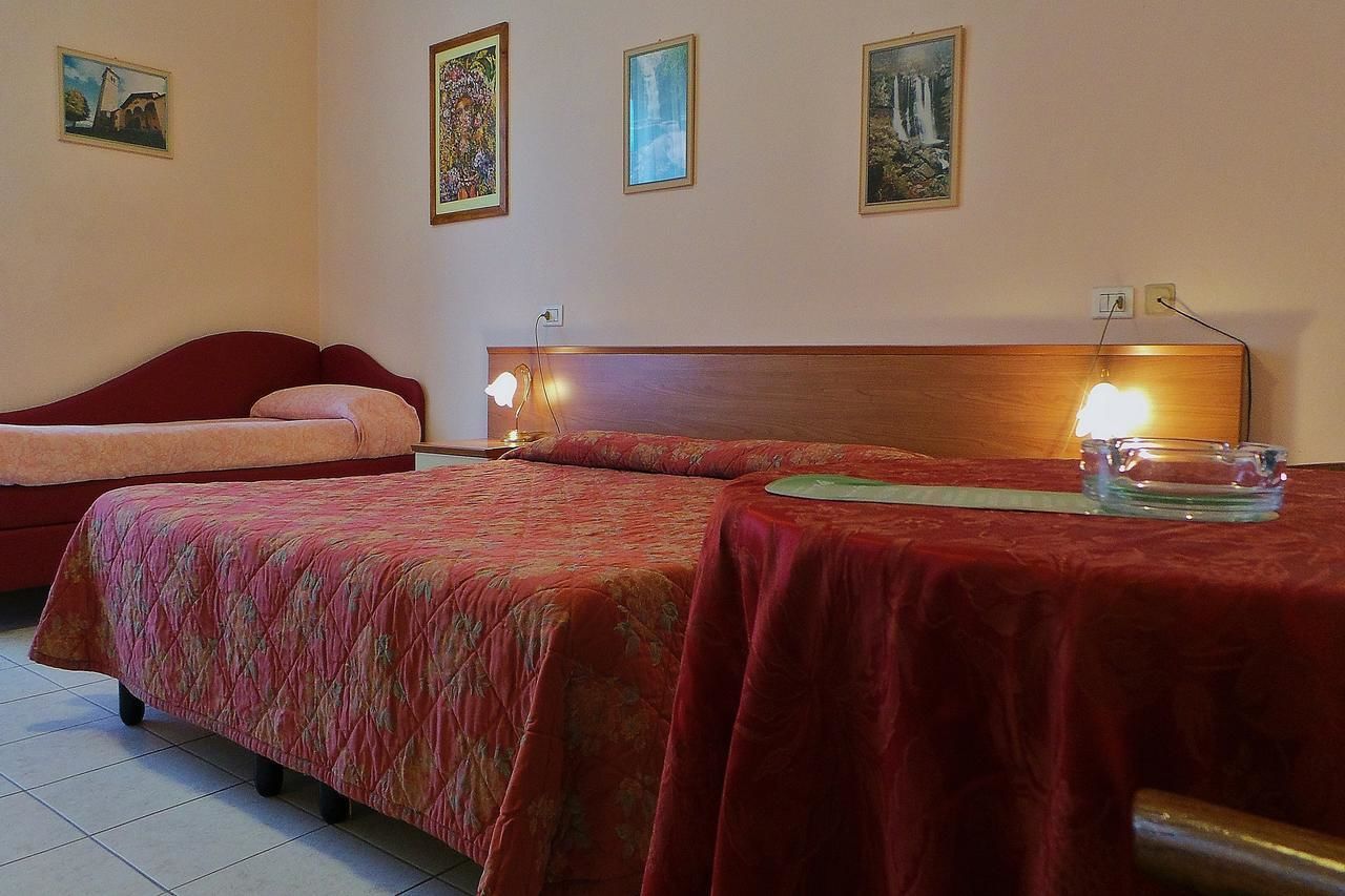 Una habitación de hotel con dos camas, un cabecero de madera y una mesita de noche con una lámpara.