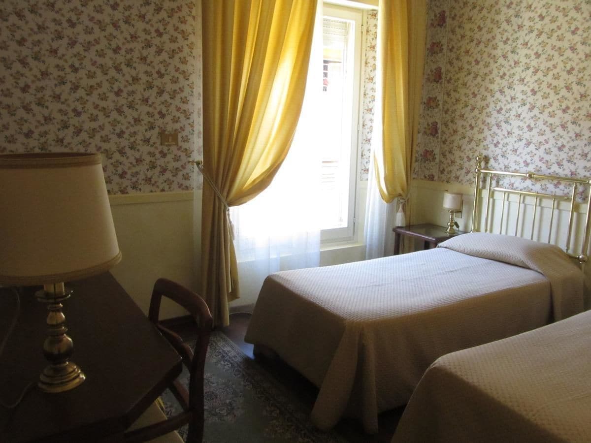A hotel room with two beds, a desk, and a chair.