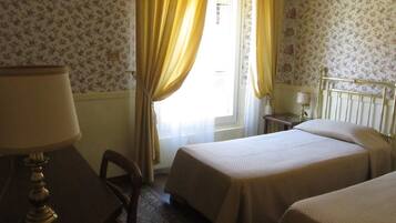 A hotel room with two beds, a desk, and a chair.