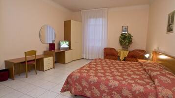 A bedroom with a bed, desk, chair, wardrobe, and a television.