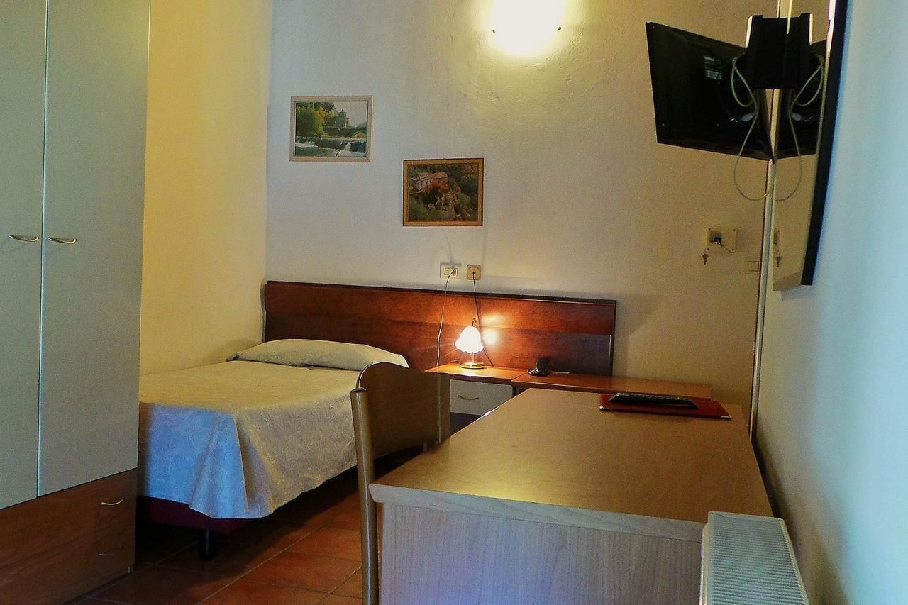 Une petite pièce simple, avec deux lits simples, un bureau, une chaise et un téléviseur fixé au mur.
