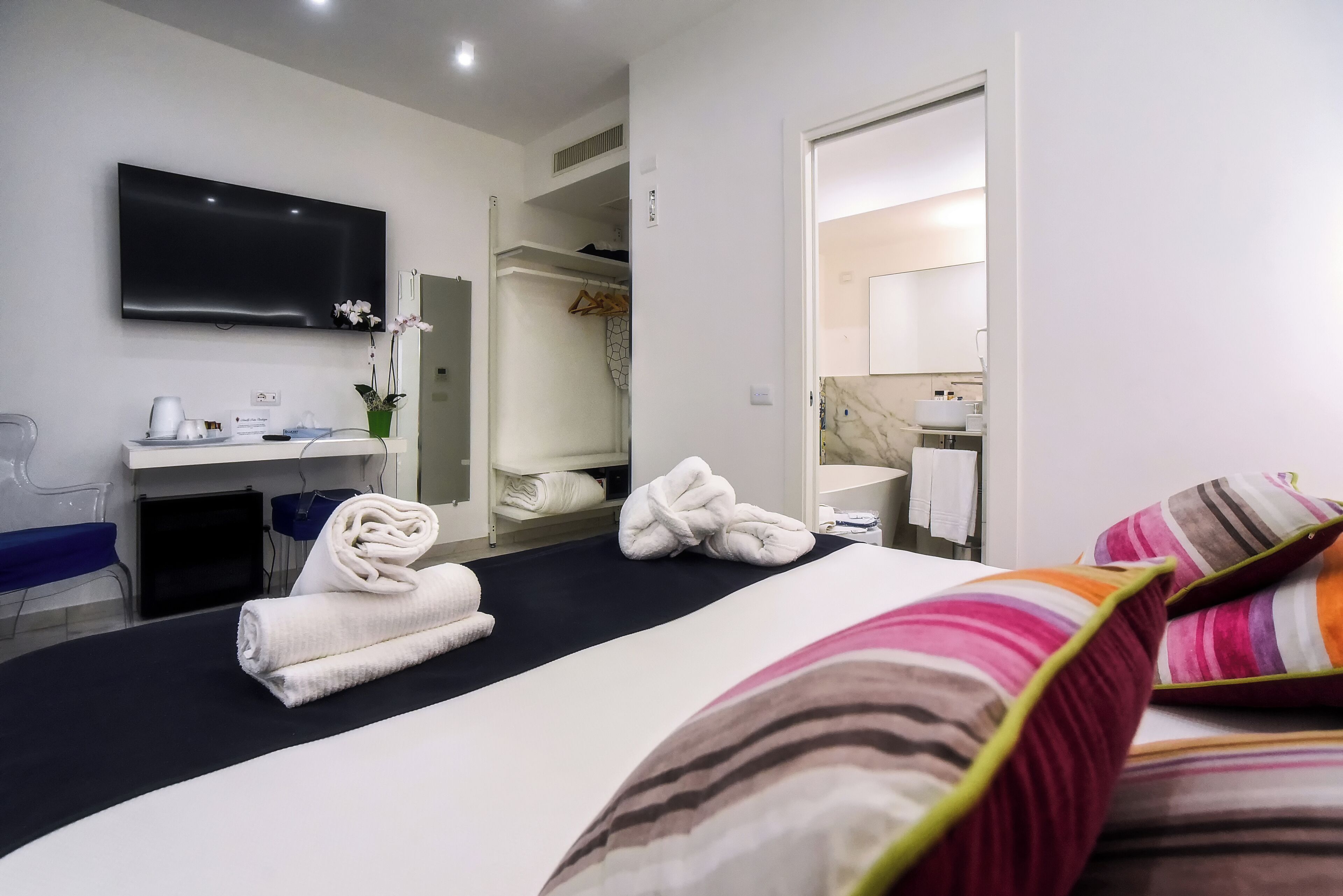 A hotel room with a bed, a TV, a desk, and a bathroom.