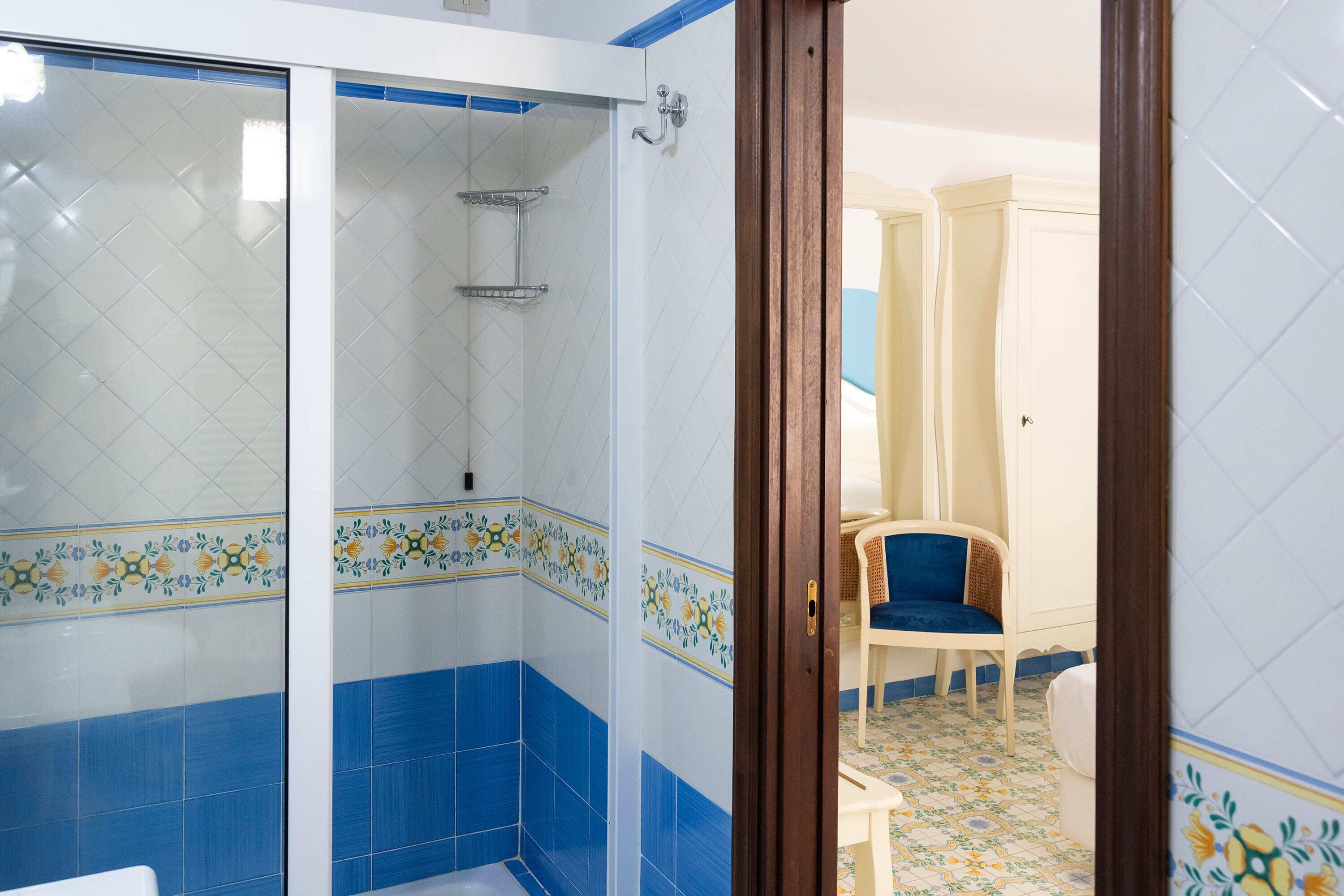 A bathroom with a shower, a toilet, and a chair.