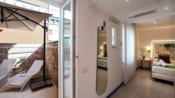 Habitación de hotel moderna con balcón, un espejo grande, una cama y una mesita con fruta.